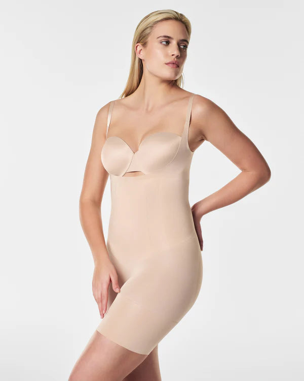 Woman wearing a beige shapewear bodysuit on a white background