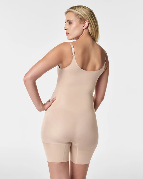 Woman wearing a beige bodysuit against a white background